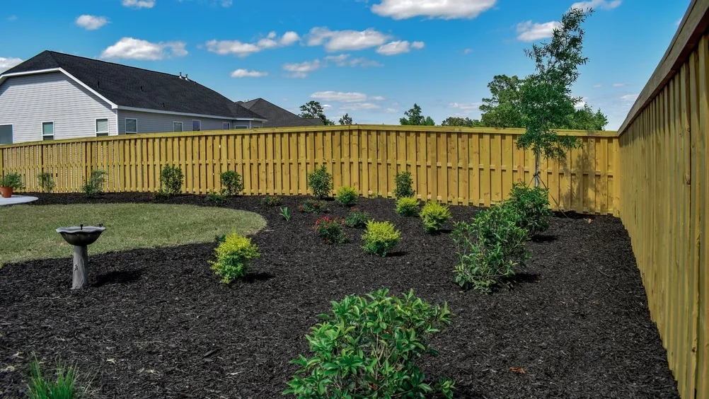 Budgeting Your Landscape: How to Use a Mulch Cost Calculator Effectively Residential outdoor garden design with green lawn, blue sky, and scattered clouds in a peaceful neighborhood setting
